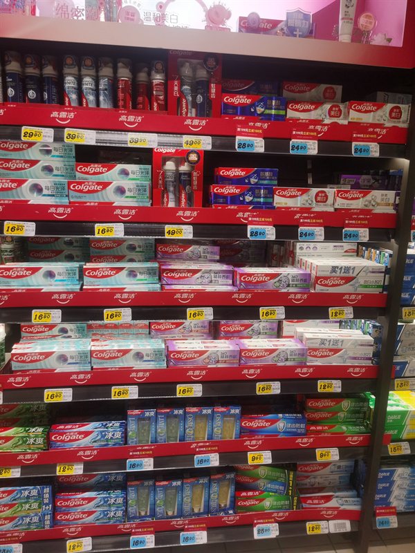 Shelves of Colgate toothpaste packs in a supermarket
