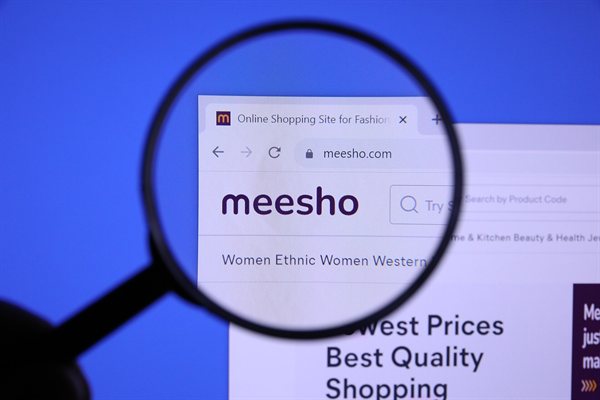 The Meesho logo on its website's homepage, seen through a magnifying glass