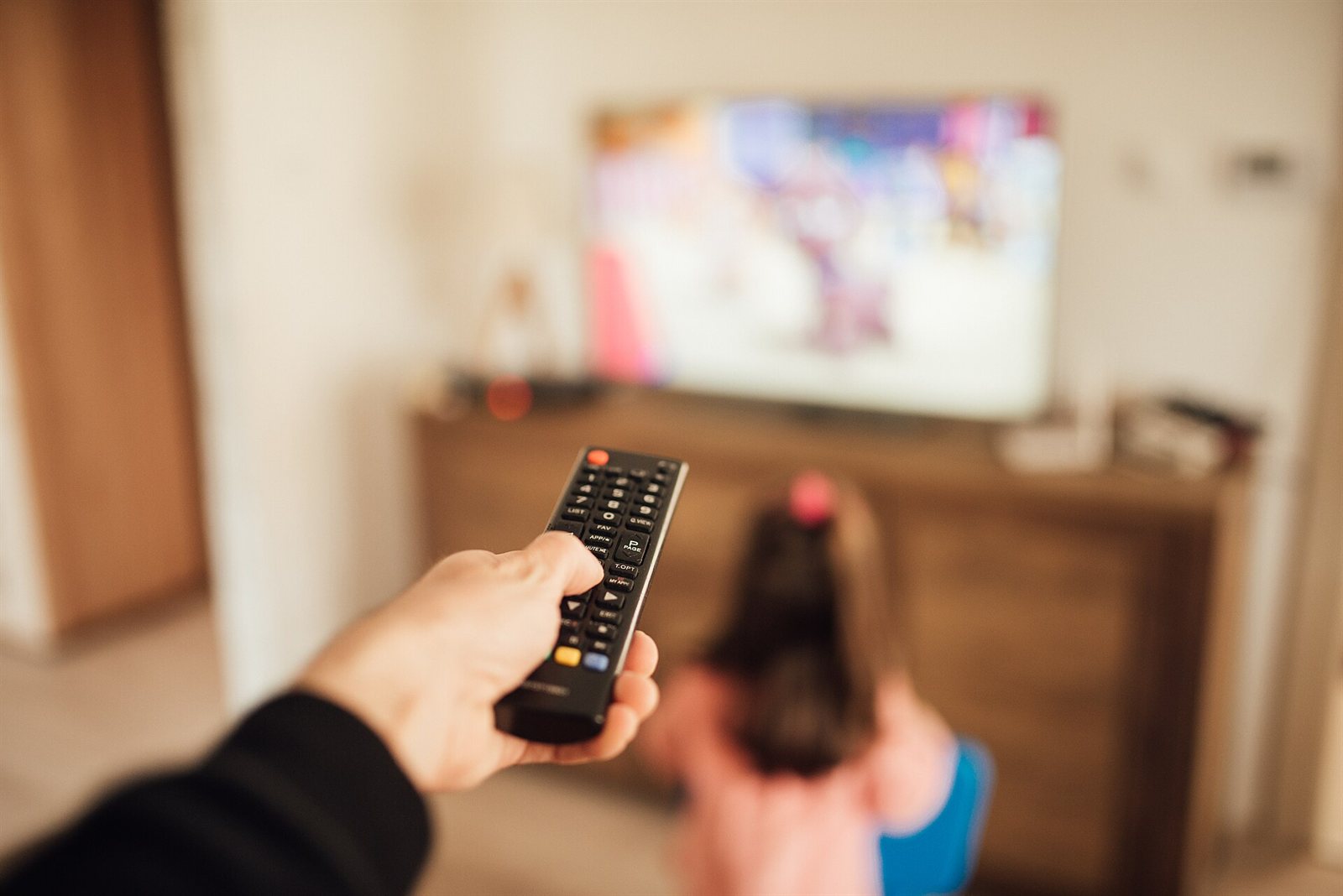 A parent using a TV remote control at home
